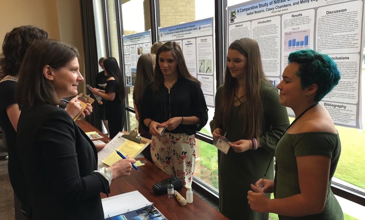 Students present their SRS poster to a scientist