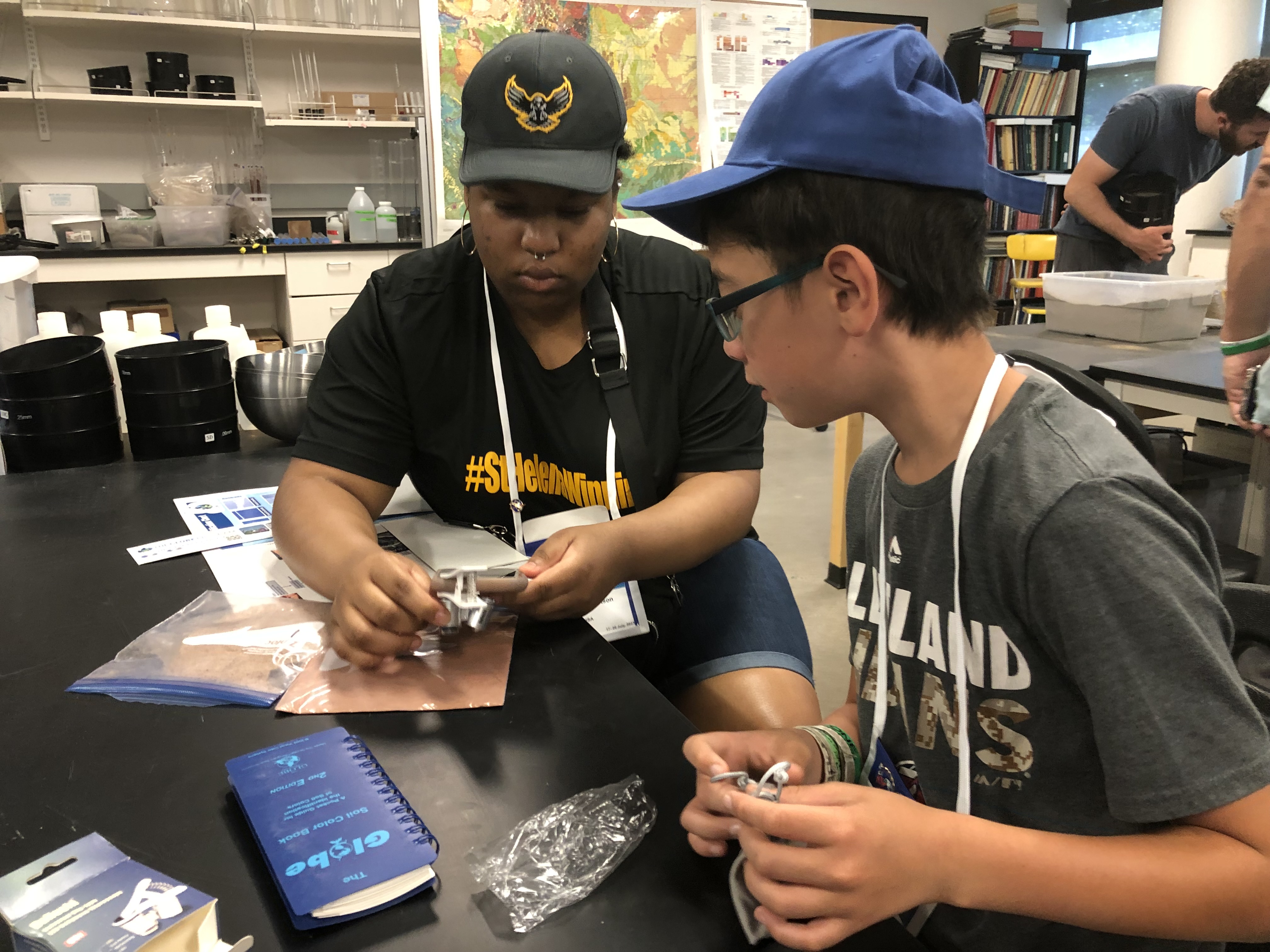 Two students at a table, working on a small device.