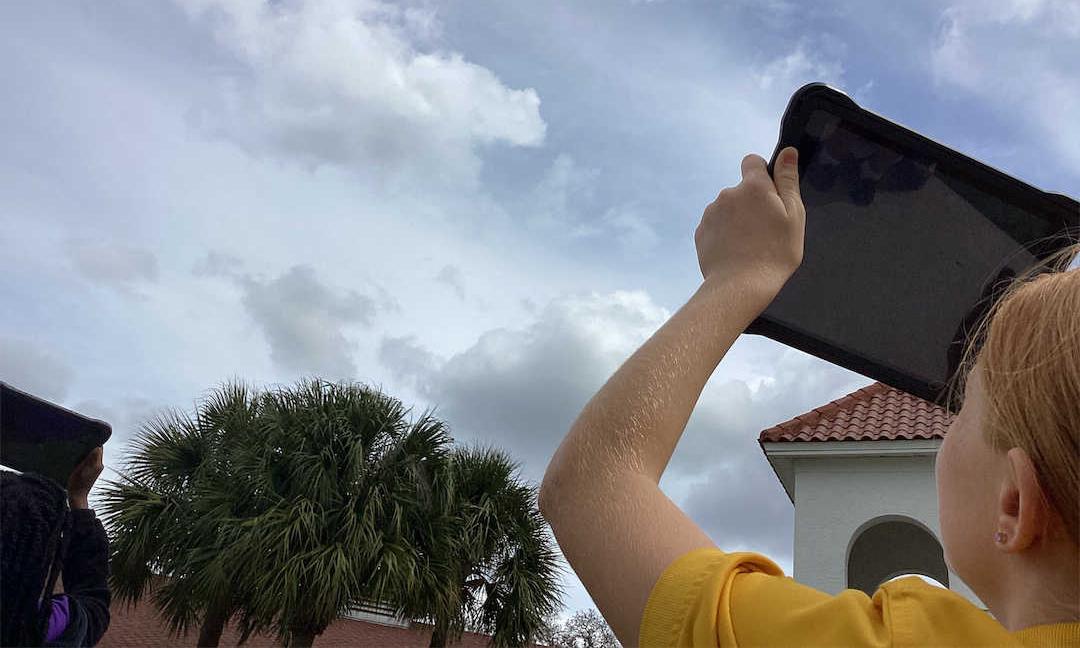 Two youth are taking a GLOBE Clouds observation using their tablets.