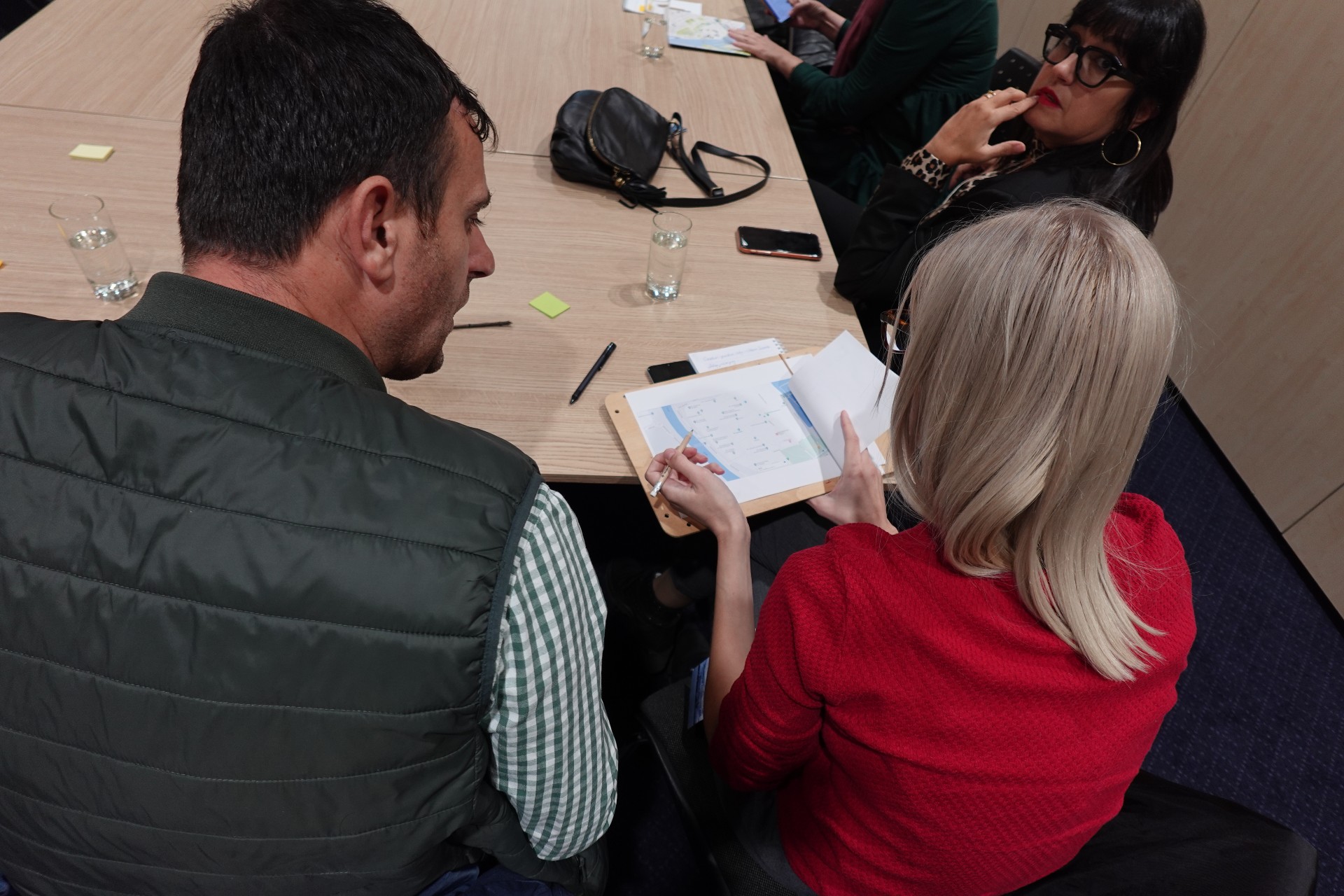 Two people sit at a table while looking at a map.