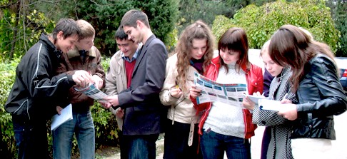 A group of people stand together while looking at brochures.