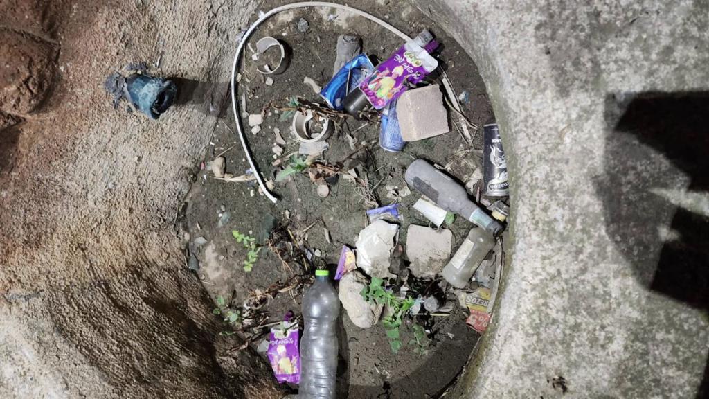 An overhead view of a small ditch, with some trash inside.