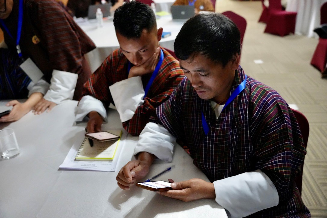 Dr. Sangay Tiger works at a table beside two other people.