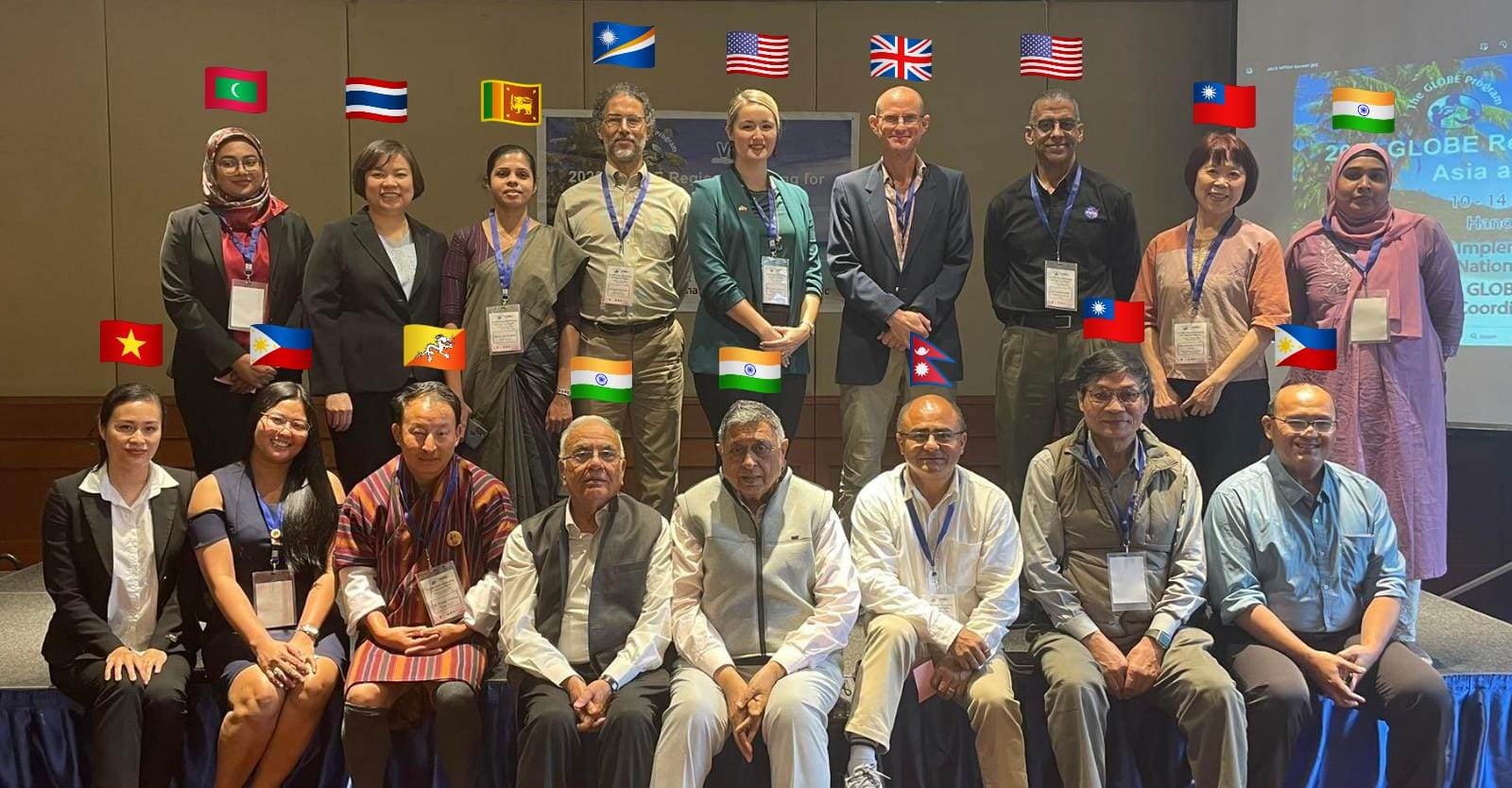 A group of people standing together for a picture. Over each person's head is a flag for their nationality.