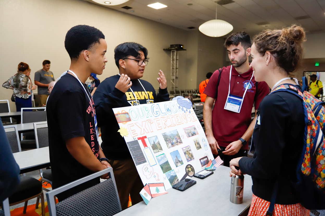 Three students showcase a presentation board, titled 'Our GLOBE Experiences.'