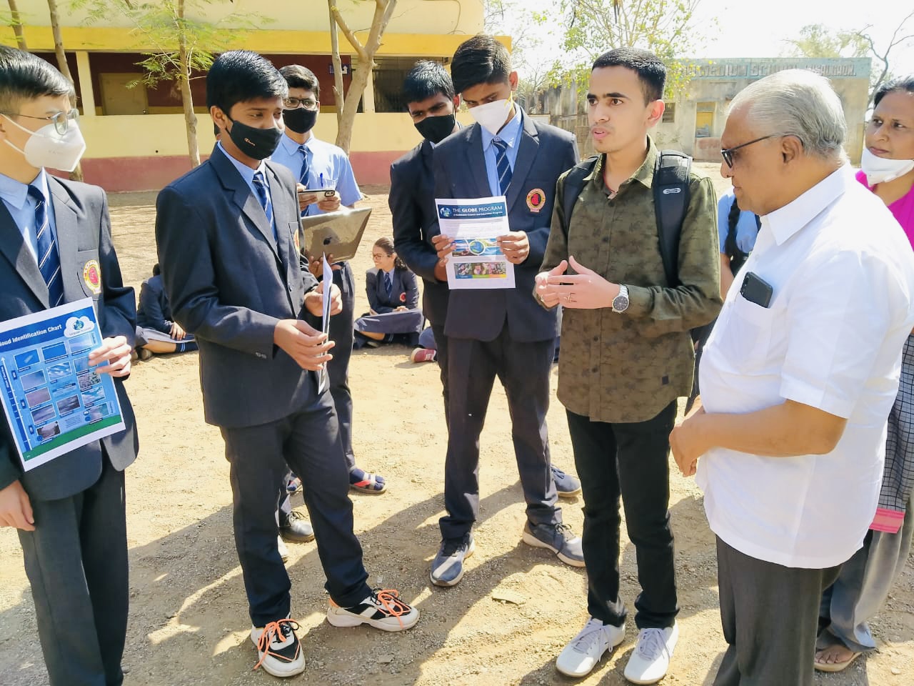 Yashraj Patil discusses GLOBE activities outside with several students and teachers.