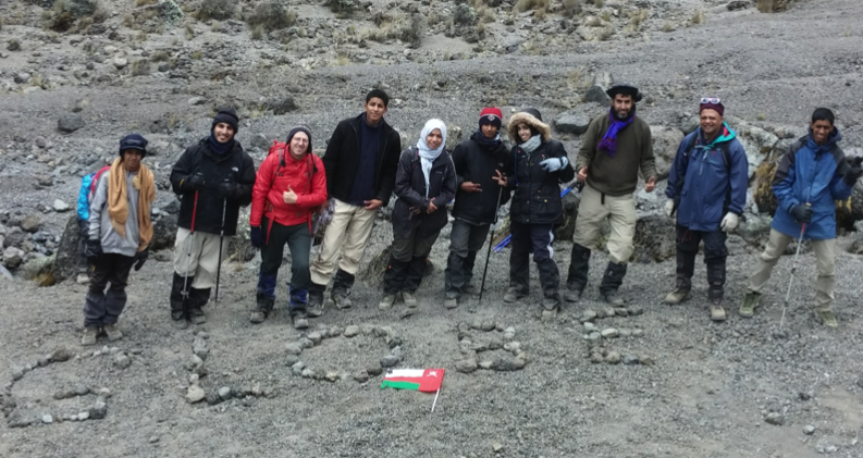 A group of people stand behind a cluster of rocks that are placed to spell: 'GLOBE."