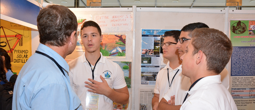 Students explain their science fair presentation to a judge.