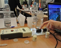 A close up of an atmosphere instrument placed on a table with a computer, books and water bottle in the background.