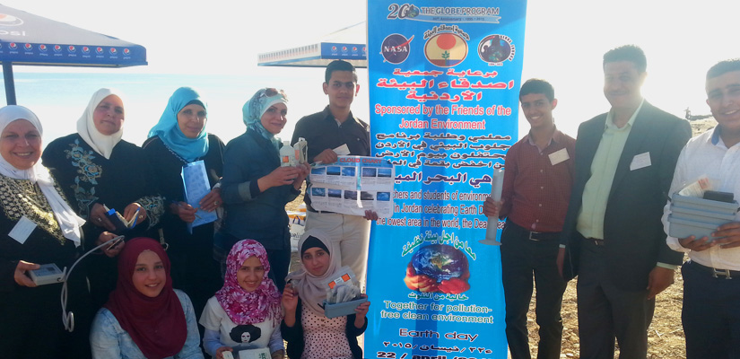 A group of teachers and student pose together for a group shot with a GLOBE banner.