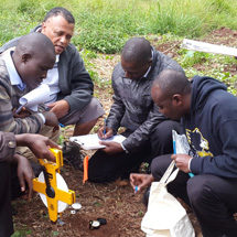 Four men work on taking soil samples together.