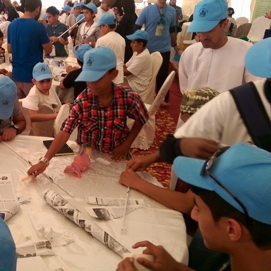 Students work together with teachers around round tables.