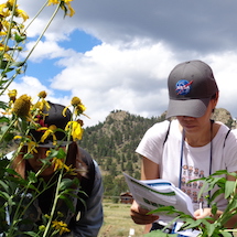 Girl in NASA hat experimenting with flowers.