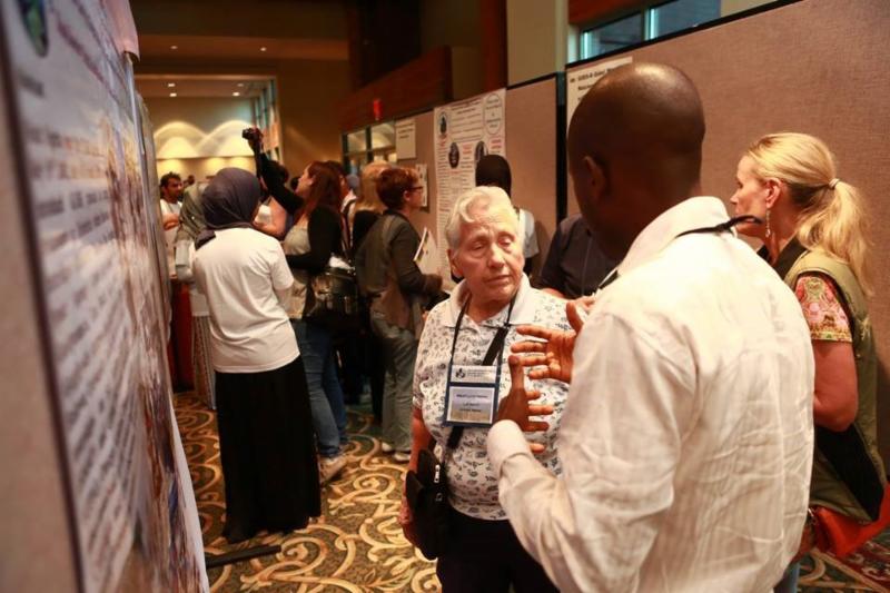 2 people with GLOBE discussing a presentation poster board at a conference. 