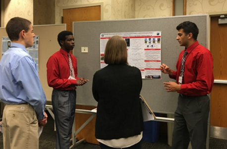 People discussing a poster board presentation. 