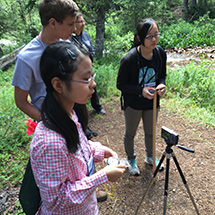 Students stand in a semi-circle out of doors.