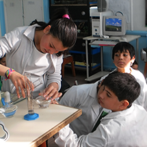 Several students watch another take a water measurement.