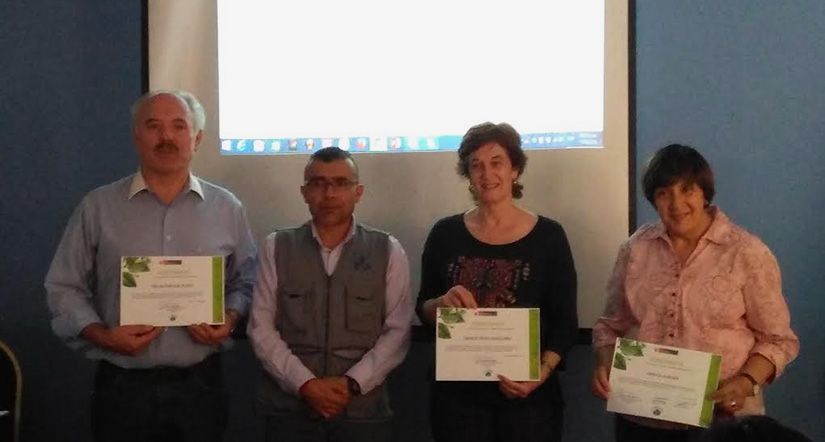 Four adults stand for a group photo and hold certificates.