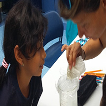 An adult explains a water sample to a young student.