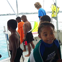 Young students stand in swimsuits and snorkeling gear after snorkeling.