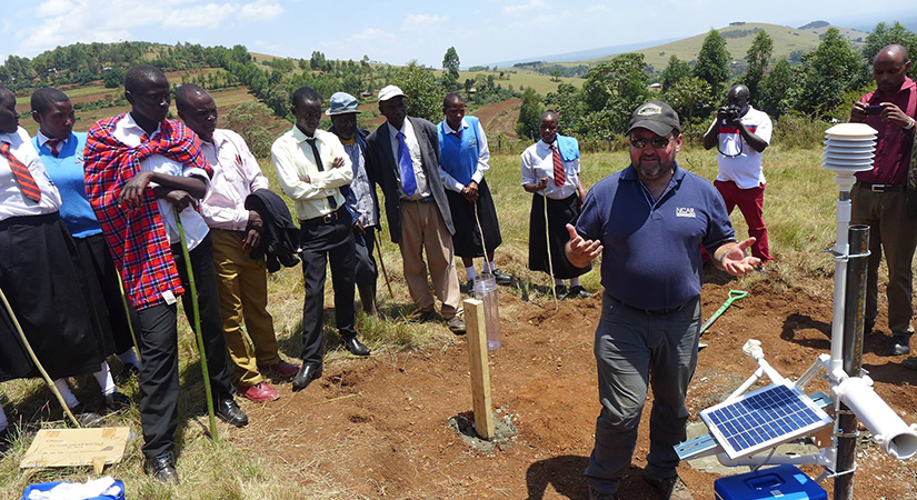 A man demonstrates a 3D weather station to a group.