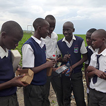 Several students stand in a group and one holds a scientific instrument.