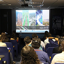 Several people watch a slideshow presentation.