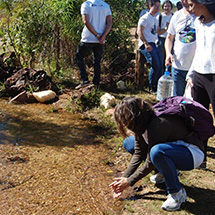 A man takes a water sample in a stream.