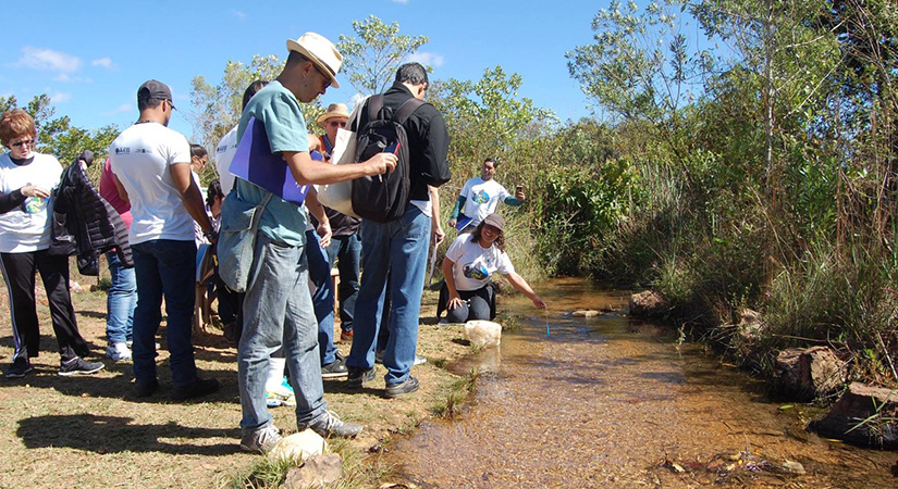Several adults stand near a stream.
