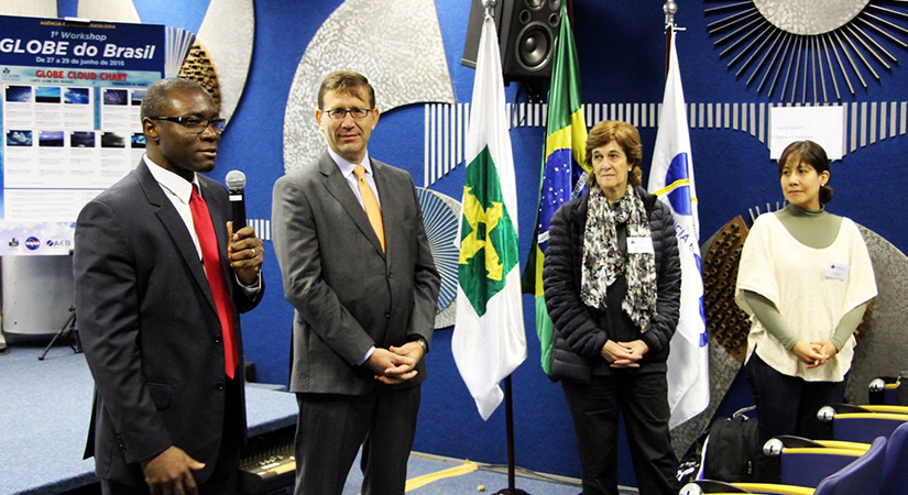 Four adults stand near flags.