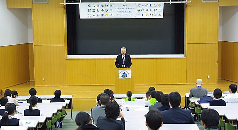 Mr. Higuchi speaking in an auditorium.