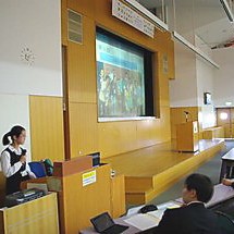 Ms. Asunama giving a talk in an auditorium.