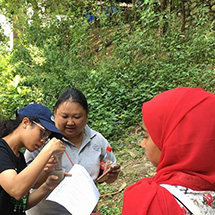 3 people looking at documents in a forest.