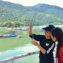 2 girls looking at an instrument in front of a lake with boats.