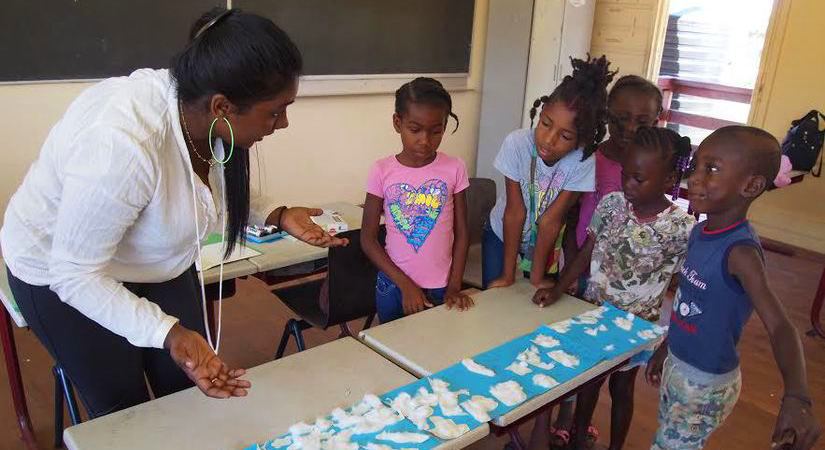 A teacher with students gathering around a table.