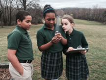 Children in green conducting field experiments in grass.