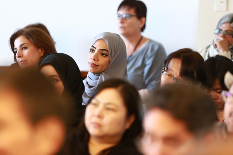 Woman in a crowd listening to a speaker. 