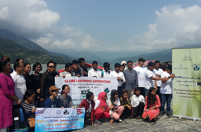 Group with GLOBE banner smiling next to lake Phewa