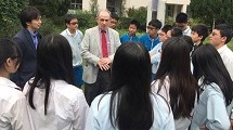 A man stands and talks within a circle of young students.