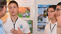 Students explain their science fair presentation to a judge.