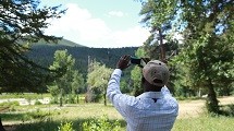 A man takes a picture of the sky with his cell phone.