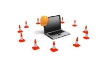 A computer with a hard hat and caution cones around it.