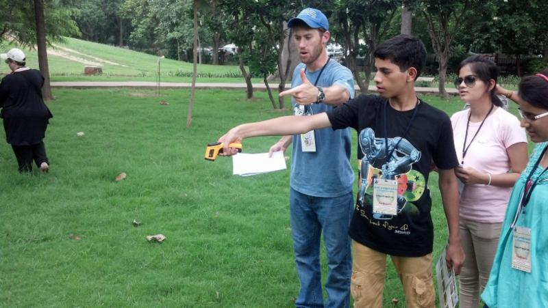 Children using tools and pointing doing science experiment.