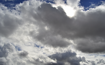 White, fluffy clouds over a sun and blue sky. 