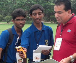 3 men looking at scientific devices in a field.