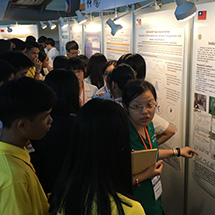 A student presents a science poster to group of other students.