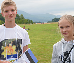 Two kids stand in an outdoor setting.