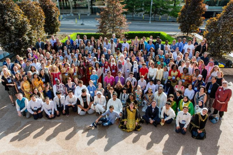 A large group of culturally dressed people stand together for a photo.