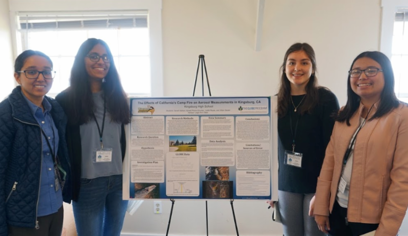 Four students stand for a picture near their science poster.