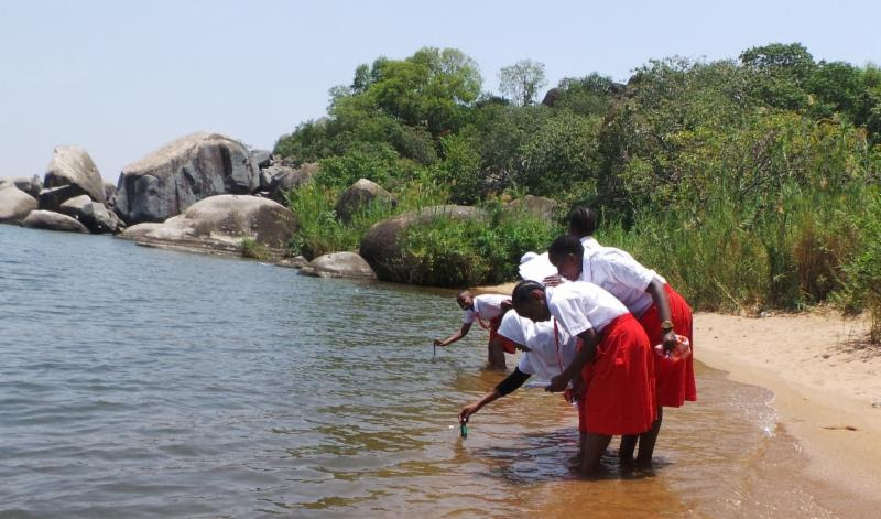 Several people take water measurements on shore.